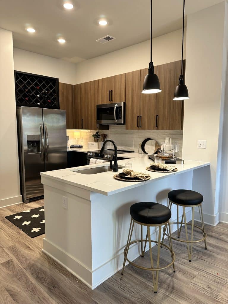 Modern apartment kitchens in apartments at Margaux Midtown with quartz countertops and wine storage about the fridge